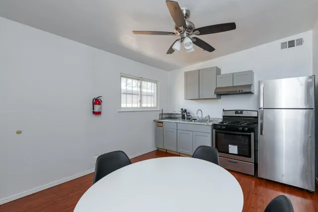 a kitchen with stainless steel appliances a dining table chairs stove refrigerator and cabinets