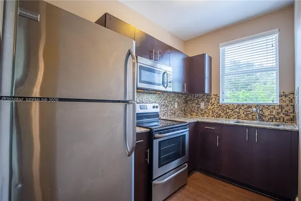 a kitchen with stainless steel appliances granite countertop a sink a stove a refrigerator and a window