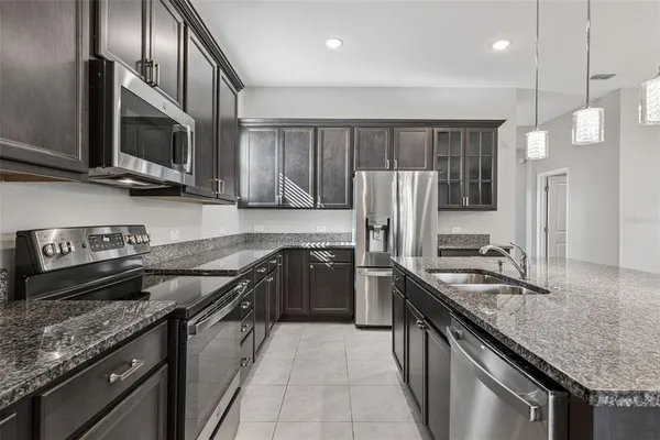 a kitchen with stainless steel appliances granite countertop wooden cabinets a stove a sink and a refrigerator