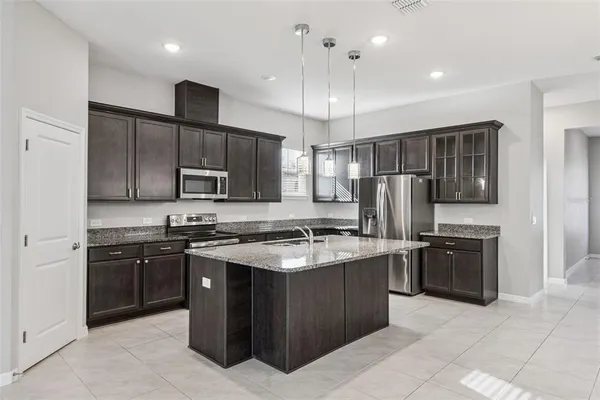 a kitchen with stainless steel appliances granite countertop a refrigerator a sink a stove a microwave and island