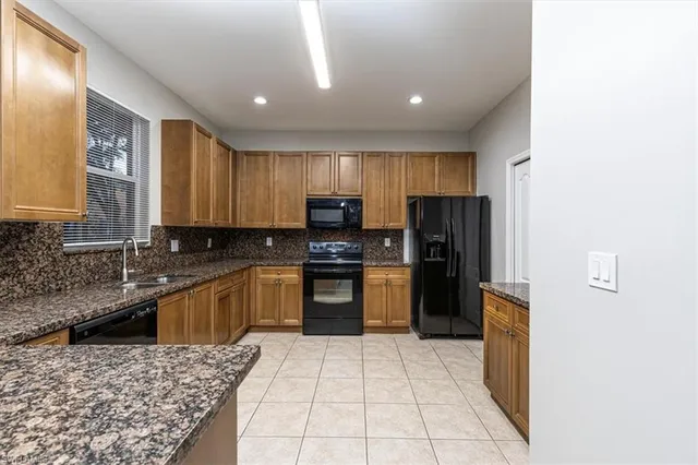 a view of an empty room with wooden floor and a kitchen