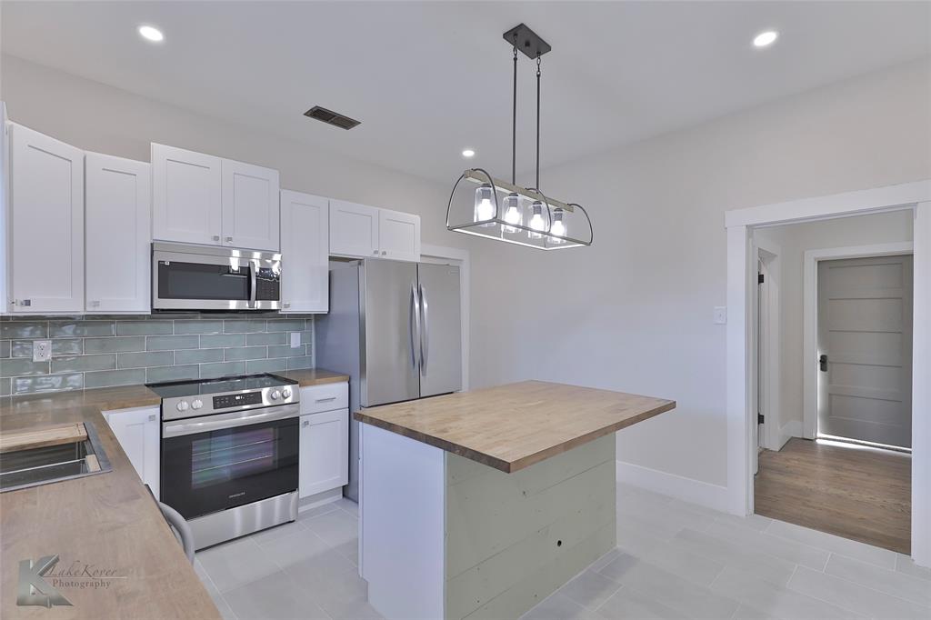 a kitchen with stainless steel appliances granite countertop a sink dishwasher stove and refrigerator with wooden floor