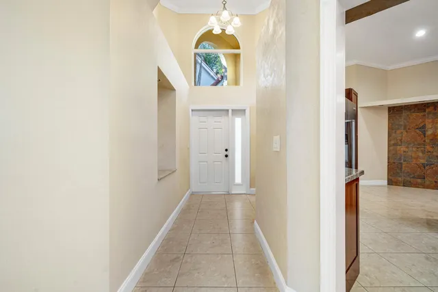 a view of hallway with a door and a chandelier