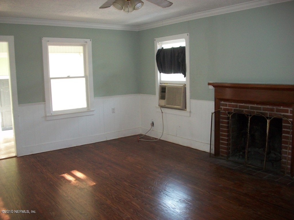 96519 Chester Road Yulee, FL 32097 - Photo 3 of 5 an empty room with wooden floor a fireplace and windows