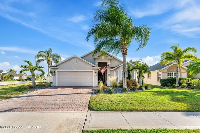 a front view of a house with a yard and potted plants