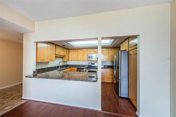 a kitchen with granite countertop wooden floors stainless steel appliances and window