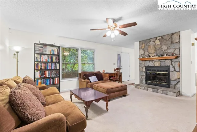 a living room with furniture a fireplace and a large window