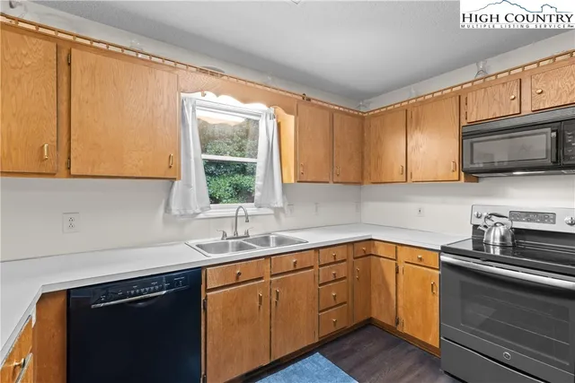 a kitchen with stainless steel appliances granite countertop white cabinets sink and window