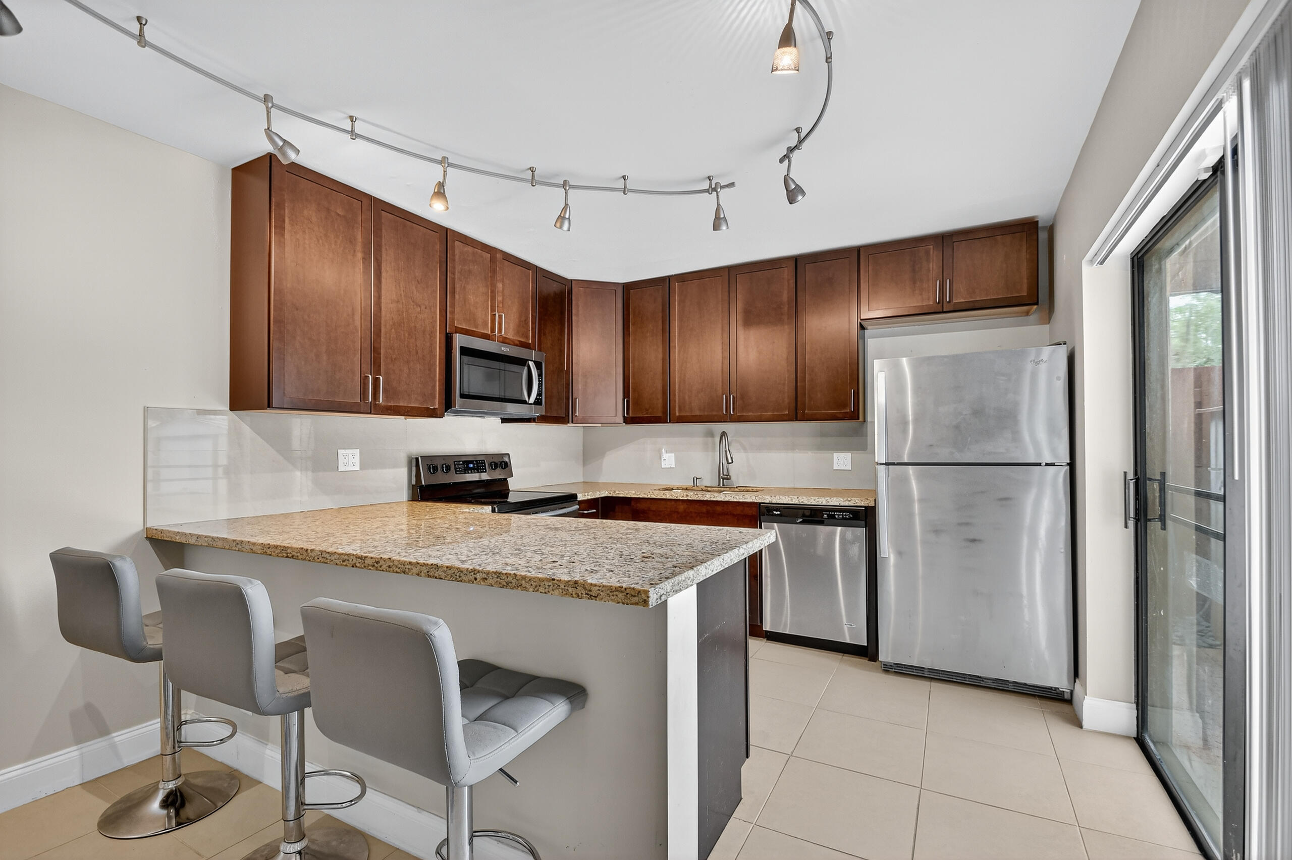 1540 Masters Circle, Unit 180 Delray Beach, FL 33445 - Photo 7 of 28 a kitchen with stainless steel appliances granite countertop a refrigerator a stove a sink and a microwave