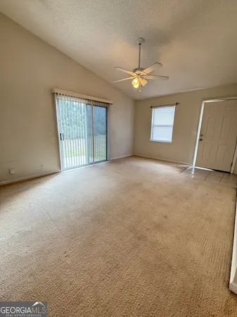 an empty room with windows and ceiling fan