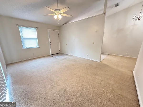 an empty room with windows and fan