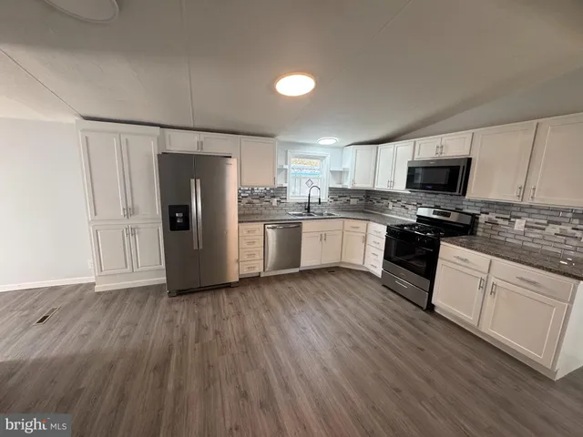 a kitchen with granite countertop a refrigerator and a stove top oven