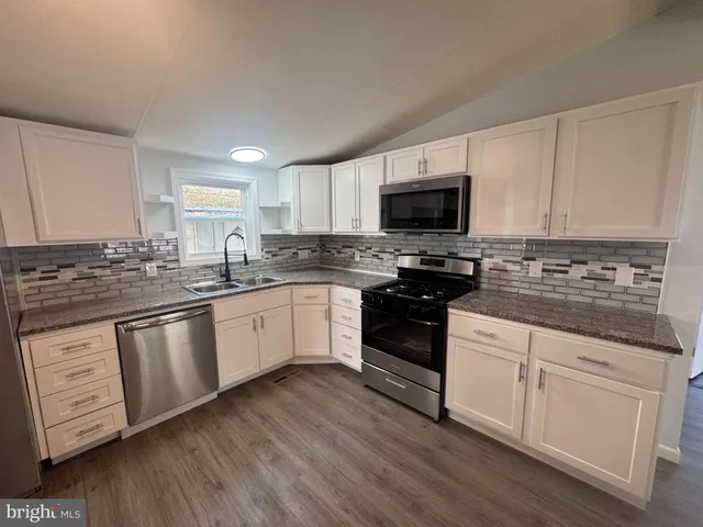 a kitchen with granite countertop a sink a stove a microwave and cabinets