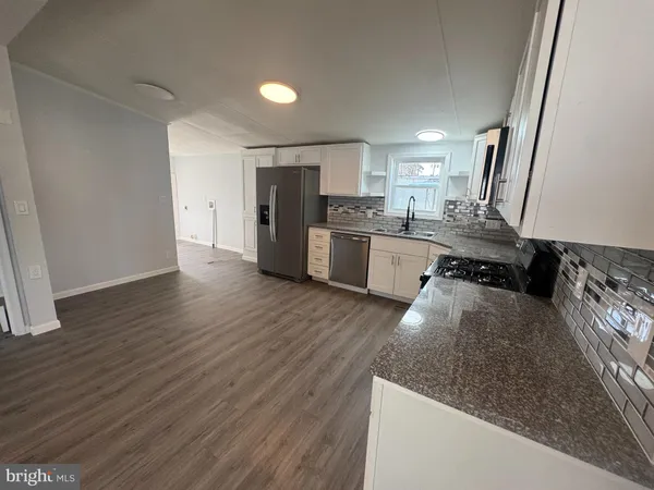a kitchen with a sink a refrigerator and wooden floor