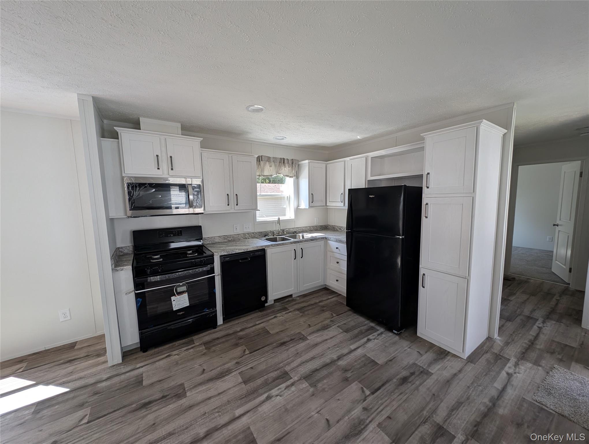 11 Square Hill Road, Unit 27 New Windsor, NY 12553 - Photo 7 of 14 Kitchen featuring a sink, white cabinetry, wood finished floors, and black appliances