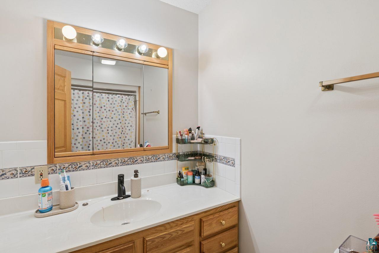 202 Prentice Heights Road Ashland, WI 54806 - Photo 12 of 28 Bathroom vanity with a wood-finish cabinet, integrated sink, and light-colored countertop