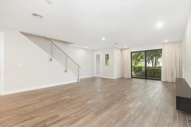 a view of an empty room with wooden floor and entryway