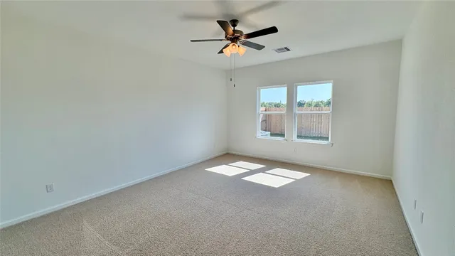 an empty room with a window and a ceiling fan