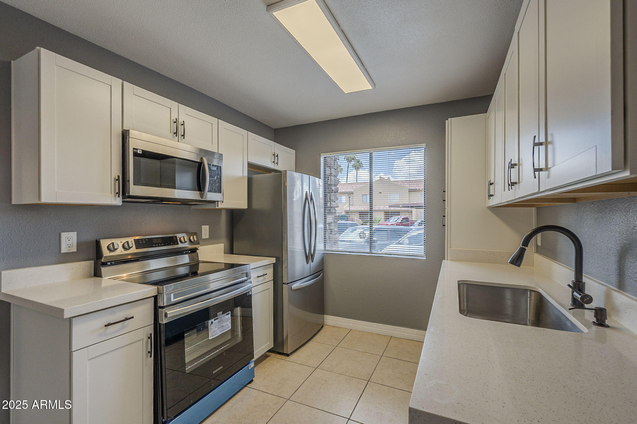 3511 East Baseline Road, Unit 1033 Phoenix, AZ 85042 - Photo 14 of 27 a kitchen with stainless steel appliances granite countertop a stove a sink and a microwave
