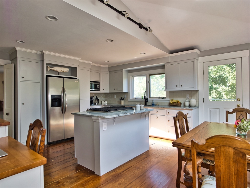 56 Maple Avenue Little Compton, RI 02837 - Photo 4 of 33 a kitchen with stainless steel appliances granite countertop a stove top oven a sink dishwasher a dining table and chairs with wooden floor