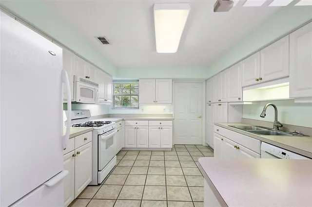 a kitchen with a sink dishwasher stove and white cabinets