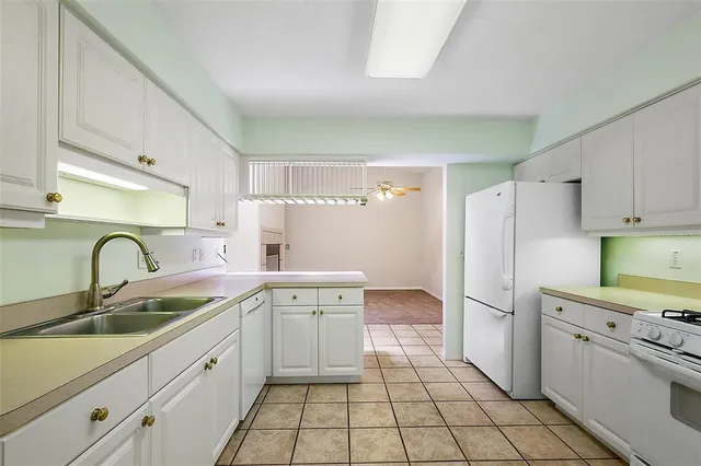a kitchen with white cabinets a sink stove and refrigerator