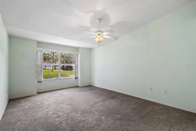 an empty room with windows and chandelier fan
