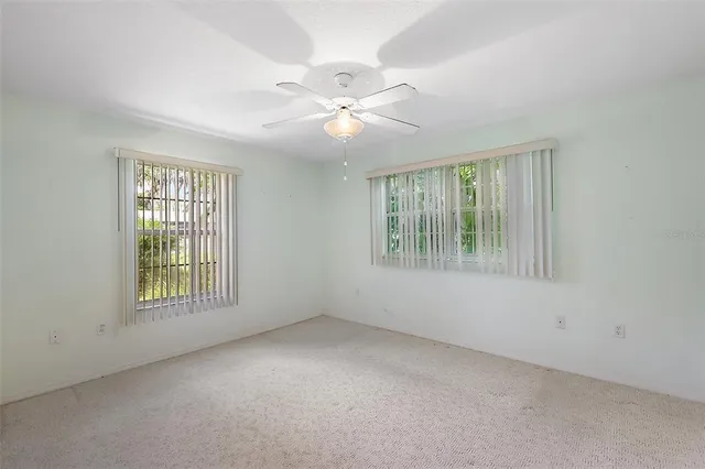 an empty room with windows and fan