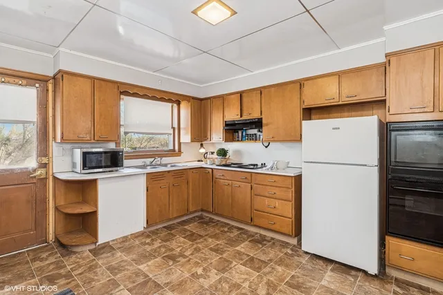 a kitchen with a refrigerator a stove a sink dishwasher and wooden cabinets