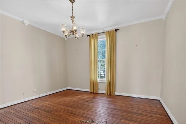 a view of an empty room with wooden floor fireplace and a window