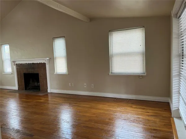an empty room with wooden floor a fireplace and windows