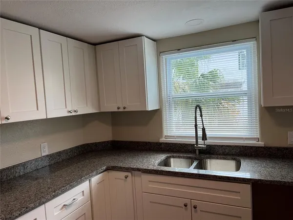 a kitchen with granite countertop white cabinets and sink