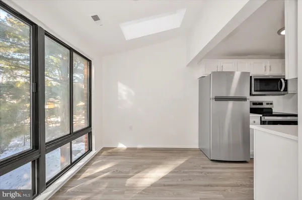 a view of a kitchen with a fridge and wooden floor