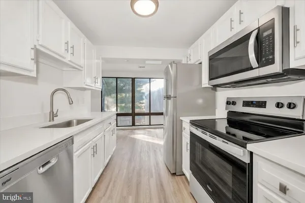 a kitchen with stainless steel appliances a stove microwave and sink