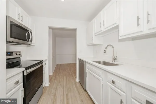 a kitchen with stainless steel appliances granite countertop a sink dishwasher stove and microwave with wooden floor