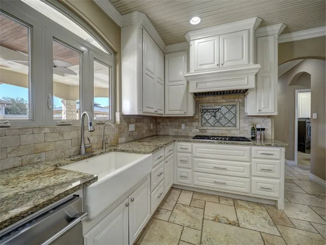 a kitchen with kitchen island granite countertop a stove sink and cabinets
