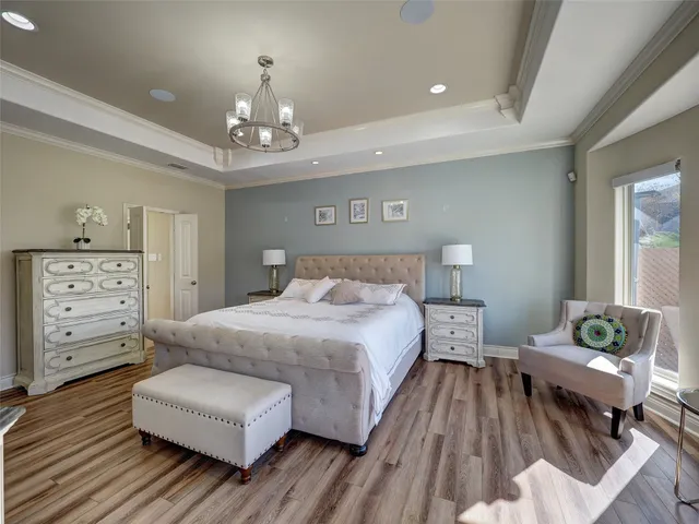 a spacious bedroom with a bed a chandelier and couch