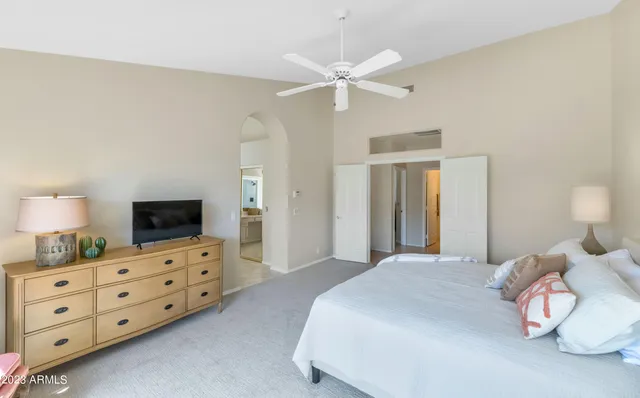 a bedroom with a bed a chandelier and a dresser