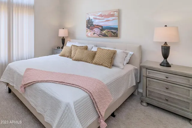 a bedroom with a bed and a lamp on dresser