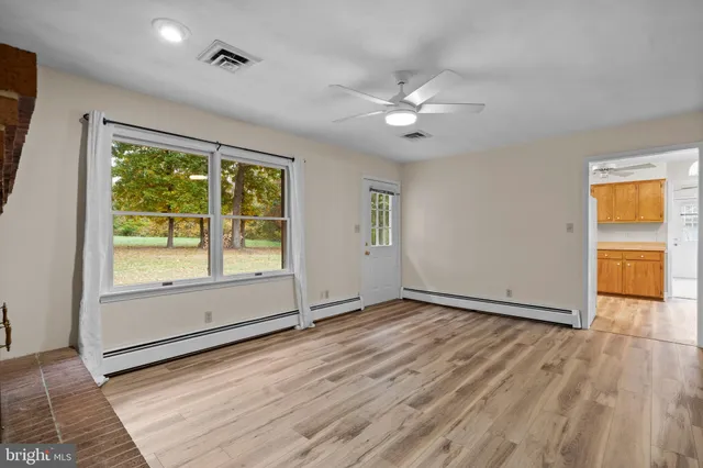 a view of an empty room with a window and wooden floor