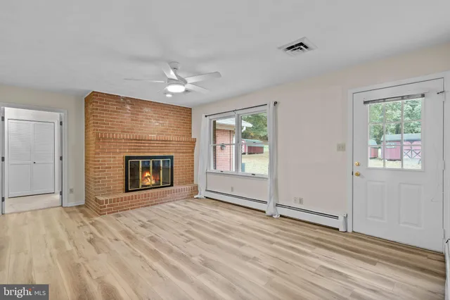 an empty room with windows fireplace and a sink