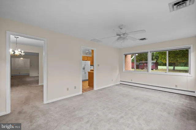 an empty room with chandelier fan and windows