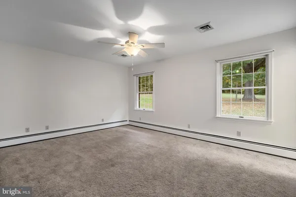 an empty room with windows and chandelier fan