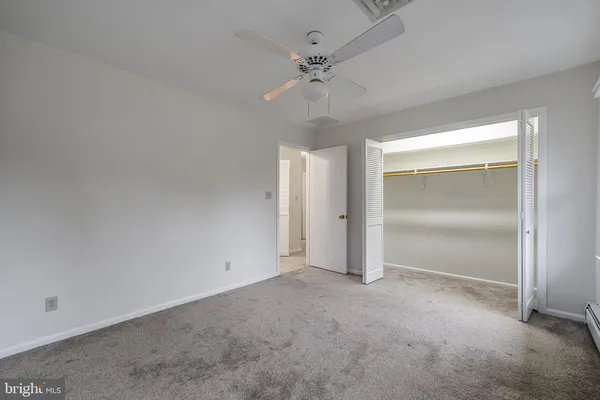 an empty room with closet and a ceiling fan