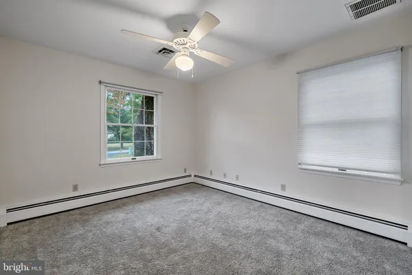 an empty room with windows and fan