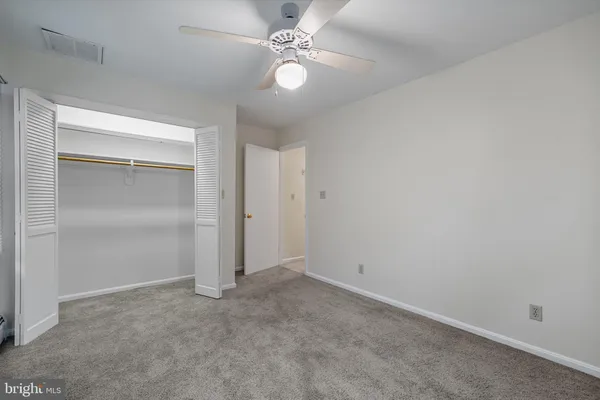 an empty room with closet and a ceiling fan