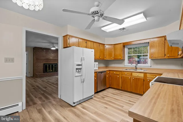 a kitchen with stainless steel appliances granite countertop a refrigerator a sink dishwasher a stove with wooden cabinets and floor