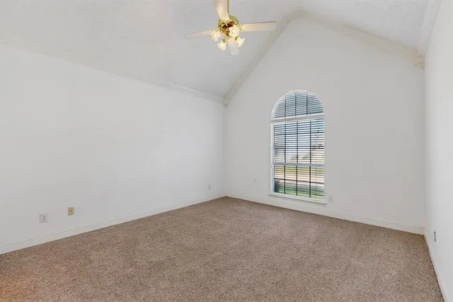 an empty room with chandelier fan and windows