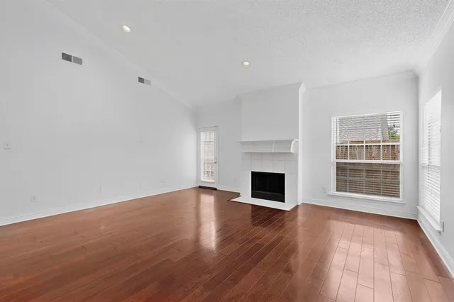 an empty room with wooden floor fireplace and windows