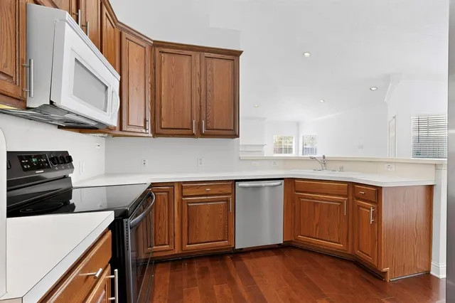 a kitchen with stainless steel appliances granite countertop wooden cabinets a stove a sink and a hard wood floors